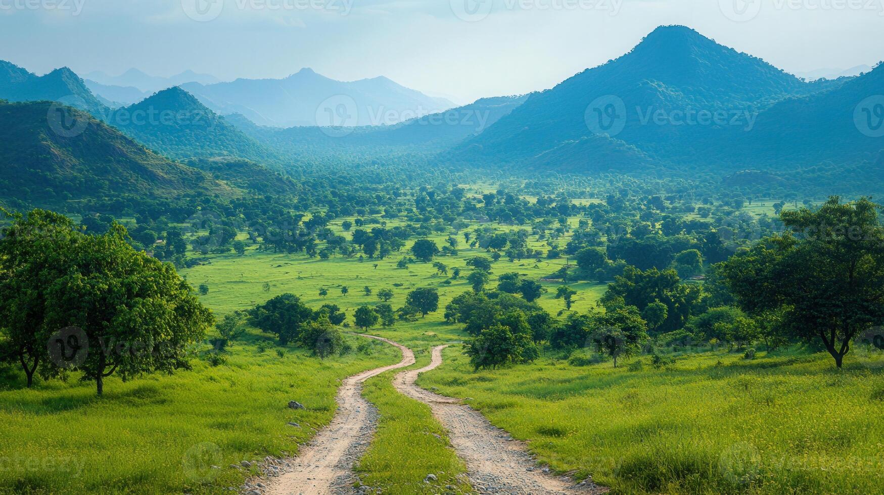 A winding road meanders through a beautiful green valley, framed by scenic hills and mountains. photo