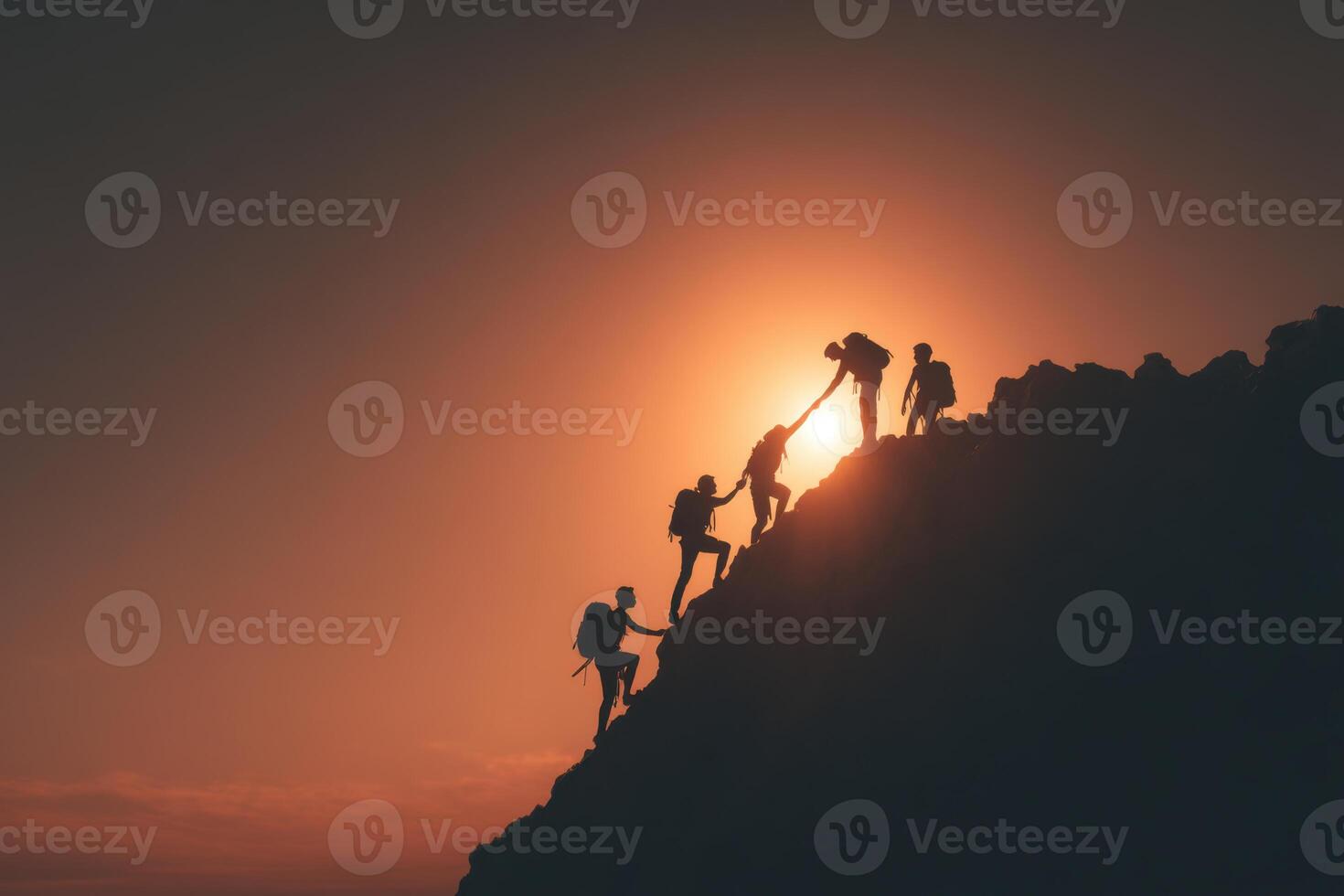 Silhouette of people climbing a mountain at sunset photo