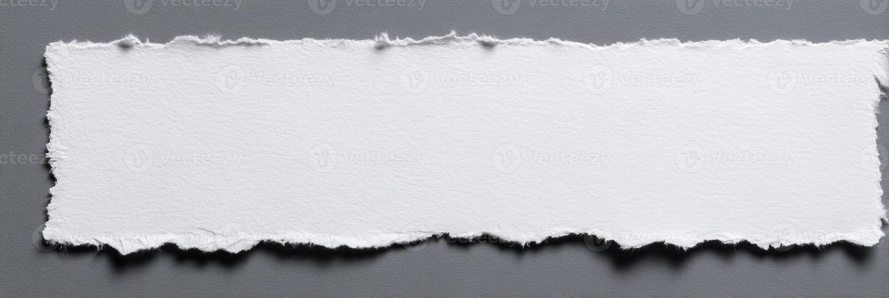 Torn Paper Piece for Textured Background and Craft Paper with Rough Edges for Scrapbooking and Design Templates on Gray Surface photo