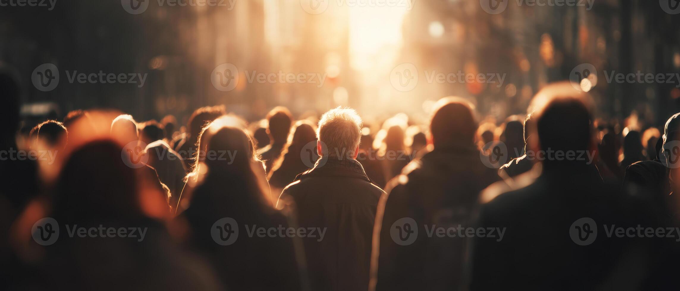 A crowd of people walking down a street at sunset photo