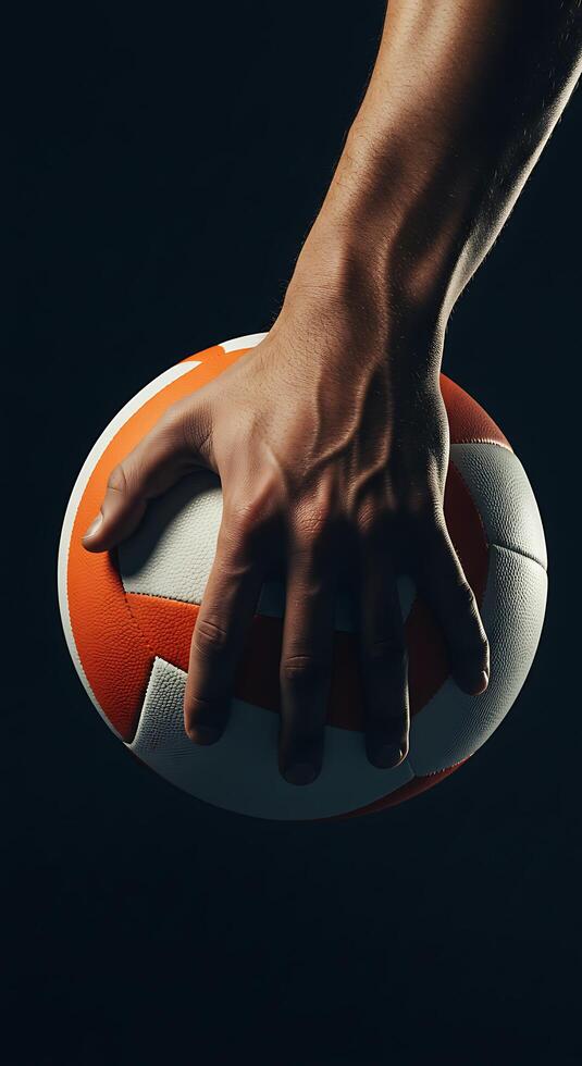 A hand holding an orange and white rugby ball photo