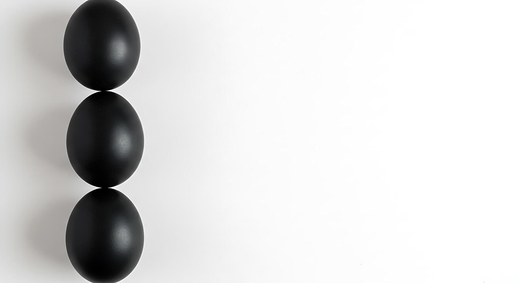 Three black eggs on a white surface photo