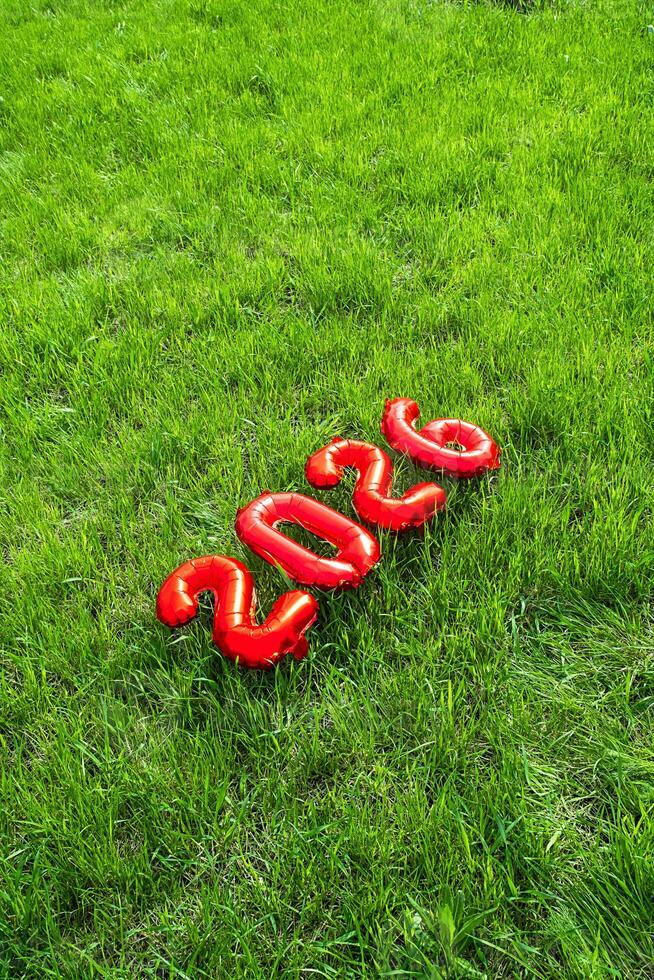 Red Foil Balloons Forming the Number 2026 on Vibrant Green Grass. Celebrating Future Date or Graduation Year Outdoors. photo