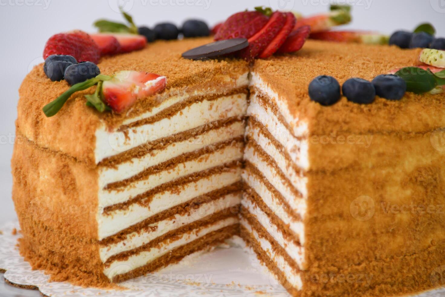 Layered Medovik Honey Cake with strawberry and blueberry slice isolated on grey background closeup side view of classic delicious cafe dessert photo