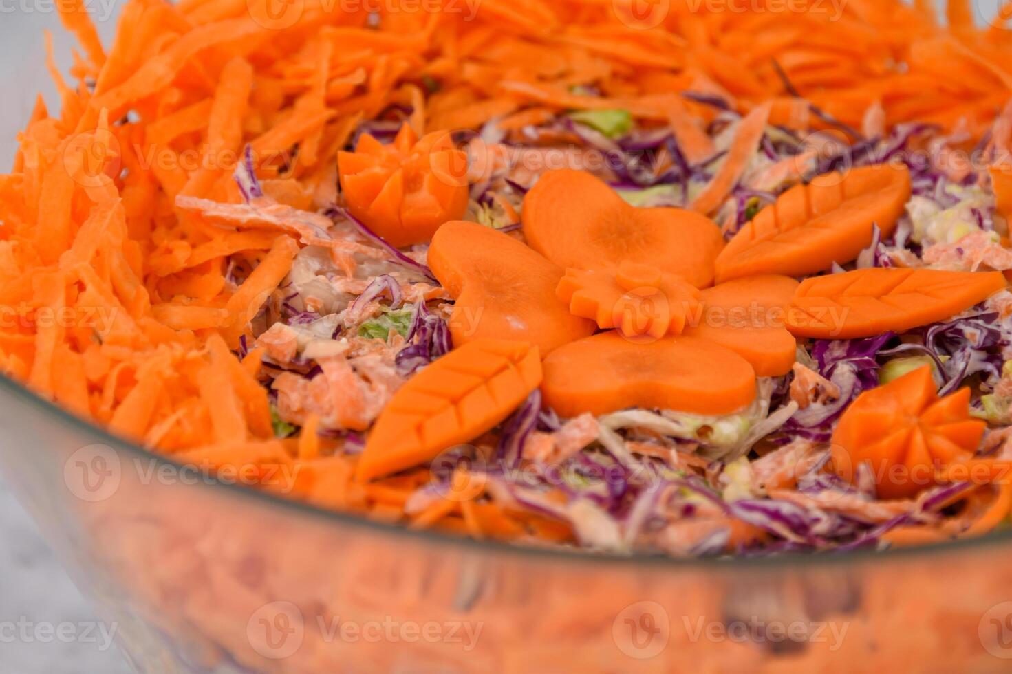Colorful Carrot and Cabbage Coleslaw Salad in a glass bowl featuring shredded green and red cabbage with a creamy sauce, topped with shredded bright orange carrots closeup view of classic salad photo