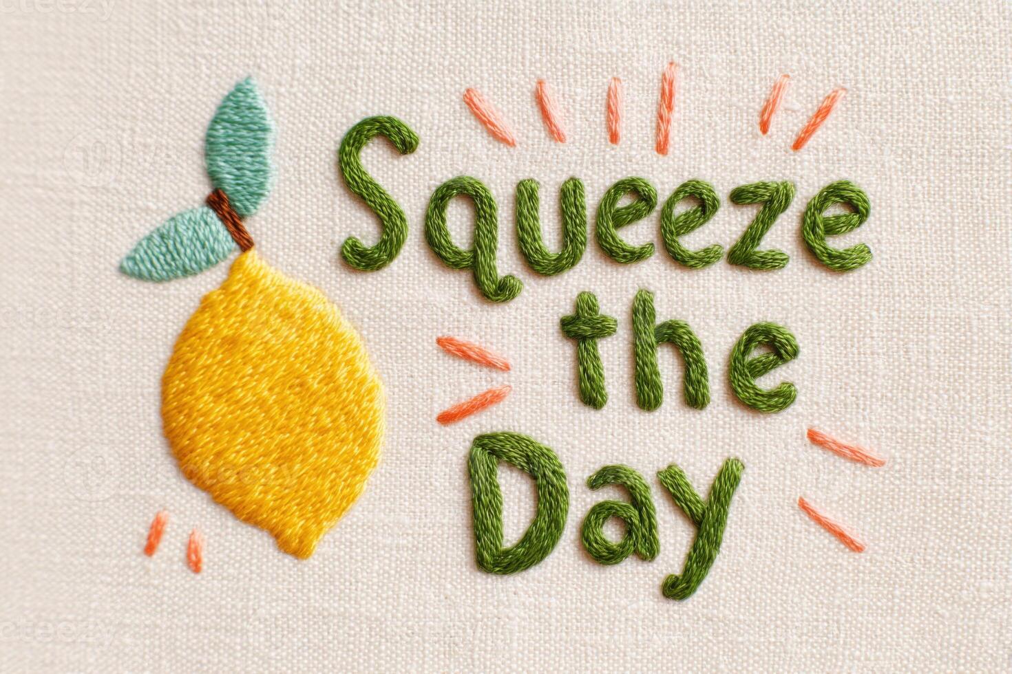 Embroidered artwork featuring a vibrant yellow lemon and playful text that reads Squeeze the Day, showcasing colorful threads on a textured fabric background photo
