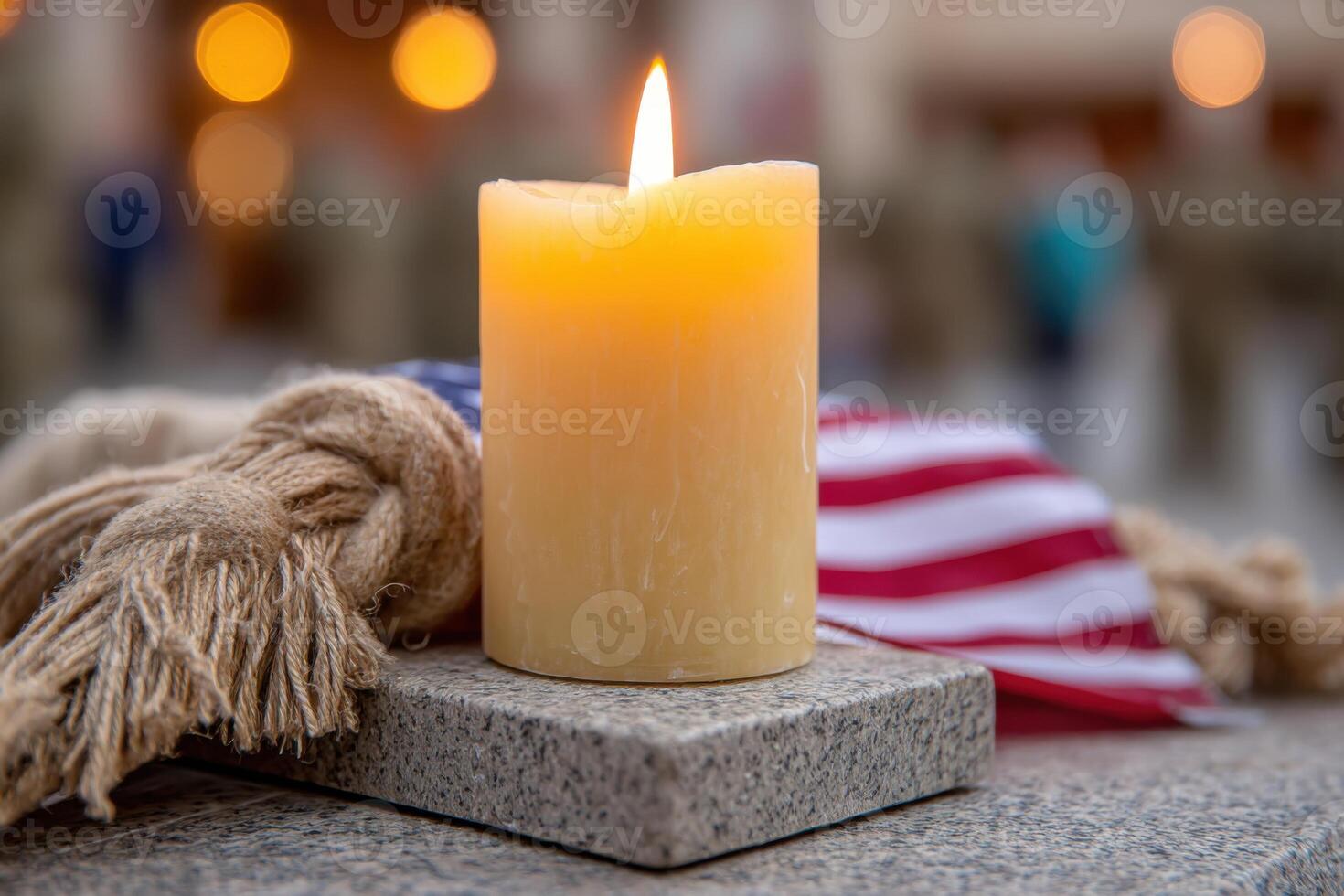 Candle lit on a stone surface beside a textured fabric, with an American flag draped nearby, symbolizing remembrance and honor during Memorial Day celebrations photo