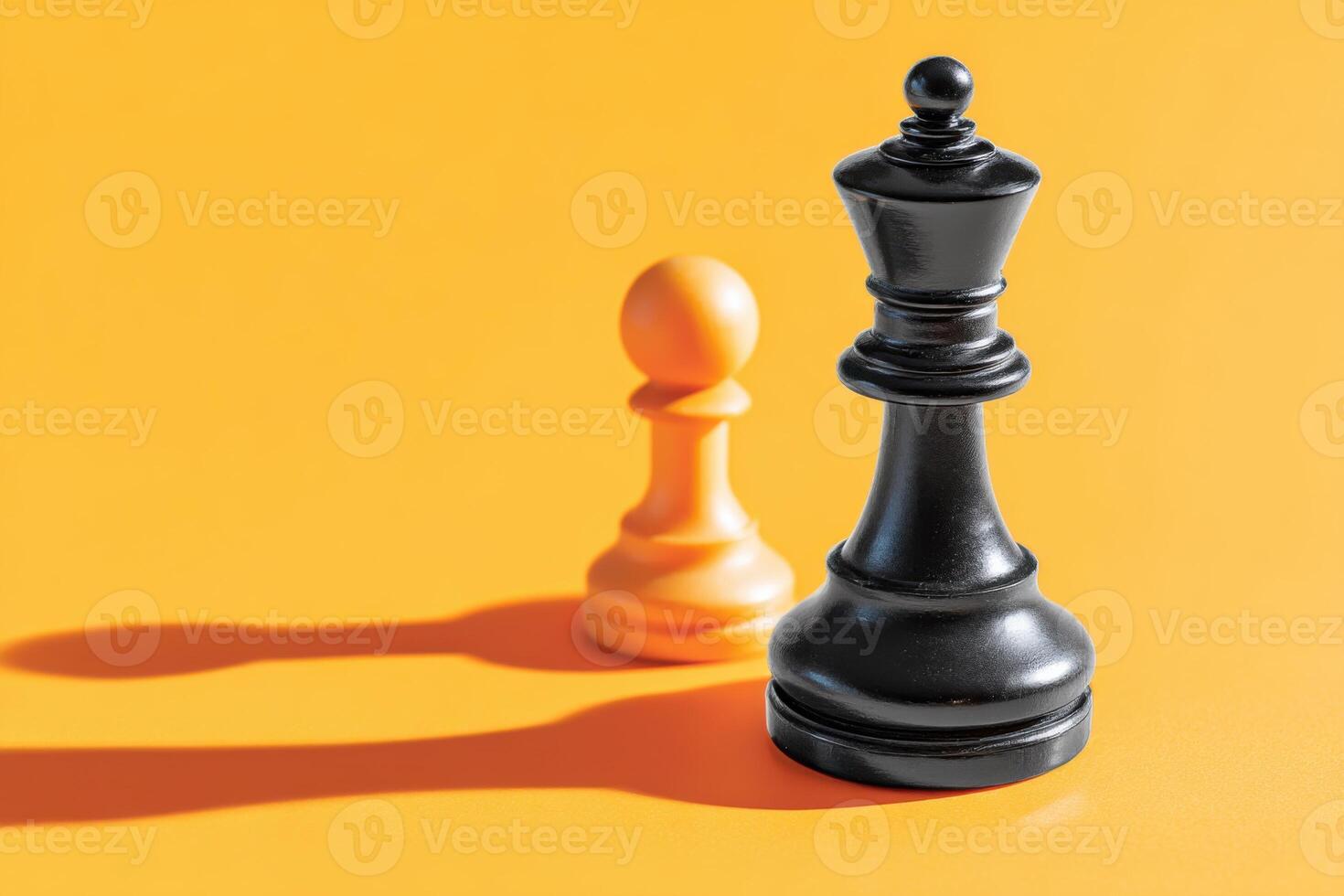 Black king chess piece stands tall beside orange pawn on vibrant yellow background, casting long shadows, symbolizing strategy and competition in the game of chess photo