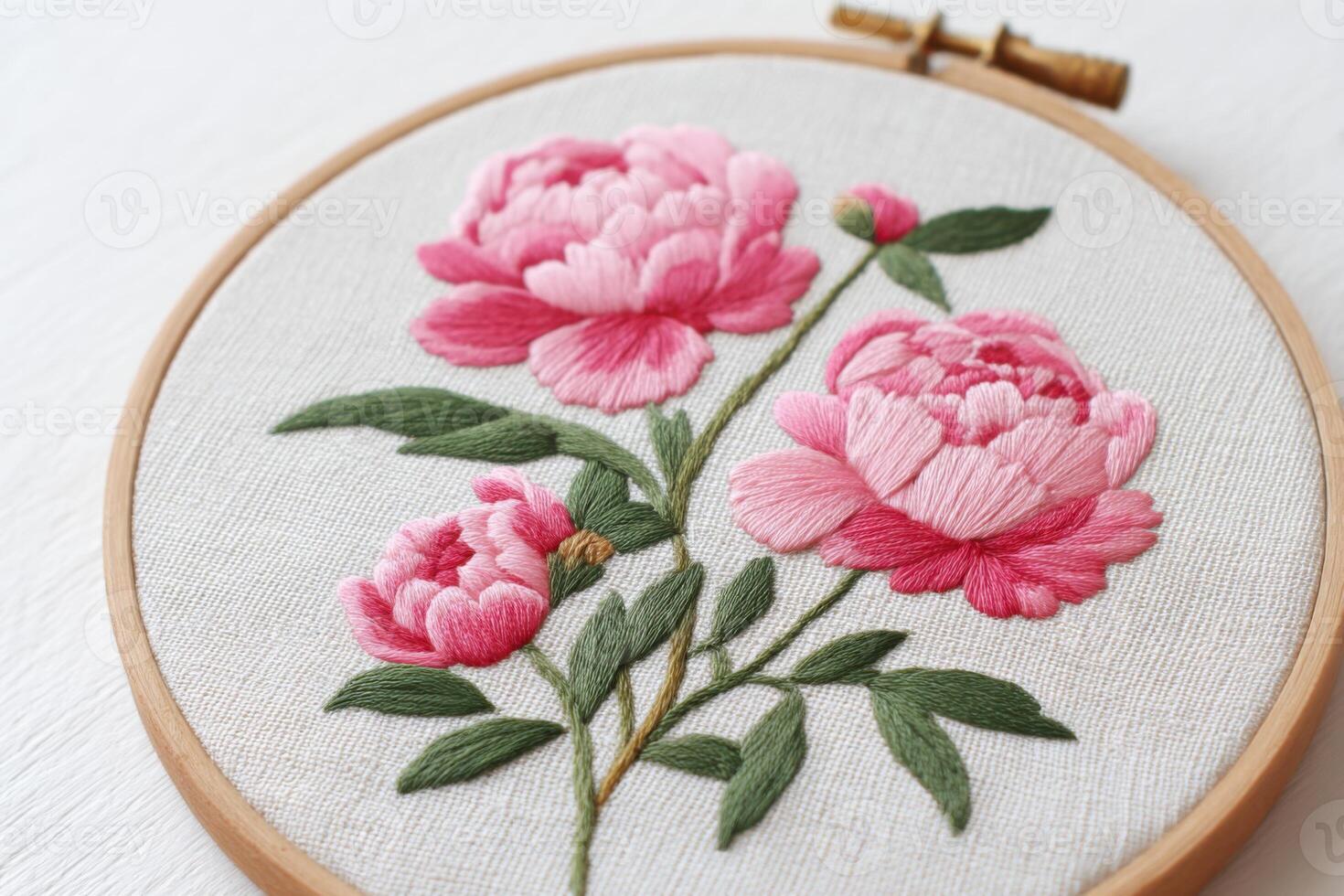Beautiful embroidery hoop featuring delicate pink peonies with lush green leaves, showcasing intricate stitching techniques and artistic craftsmanship in textile art photo