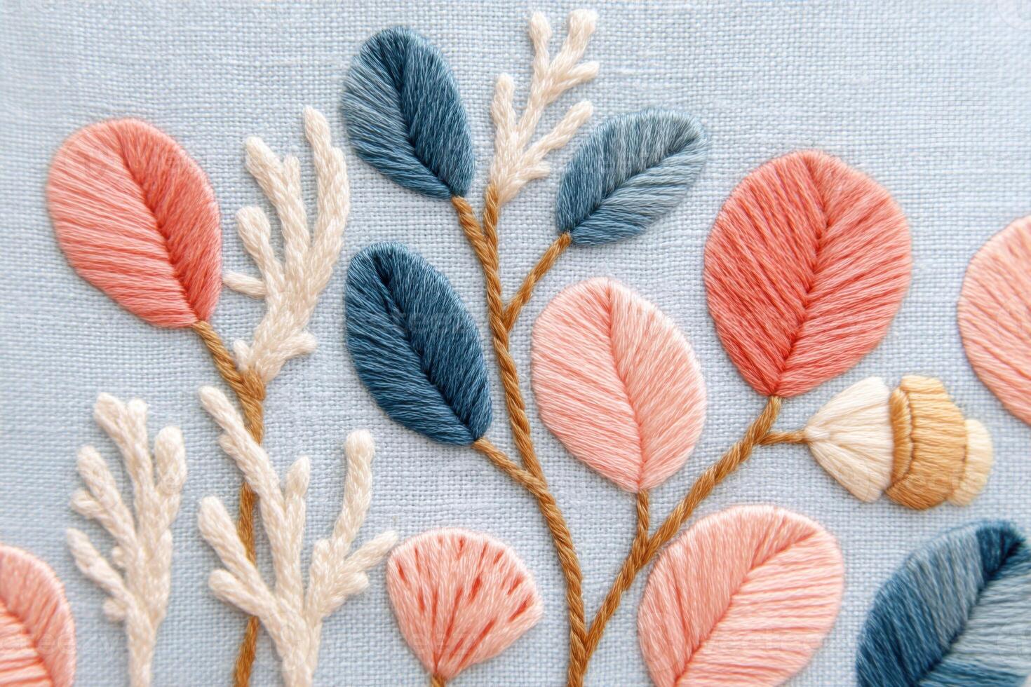 Colorful embroidery design featuring intricate floral patterns with various leaves and textures on a soft blue fabric background, showcasing artistic craftsmanship and creativity photo
