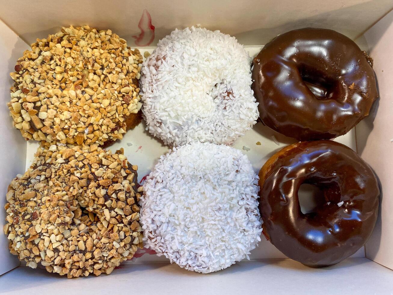 Donuts with different flavors and toppings lie in a box photo
