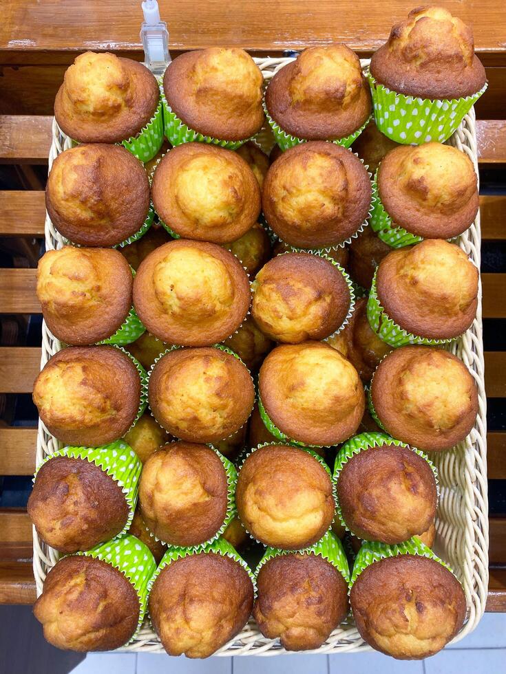 Freshly made cupcakes are laid out in a row on the counter in the store, vertical picture photo