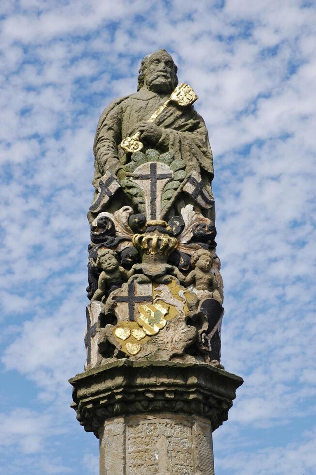 A statue of a man holding a cross on top of a pillar photo