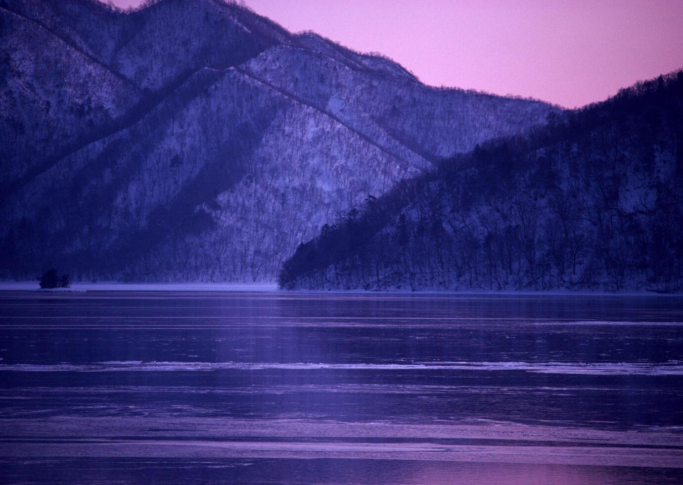 a lake with mountains in the background at sunset. photo