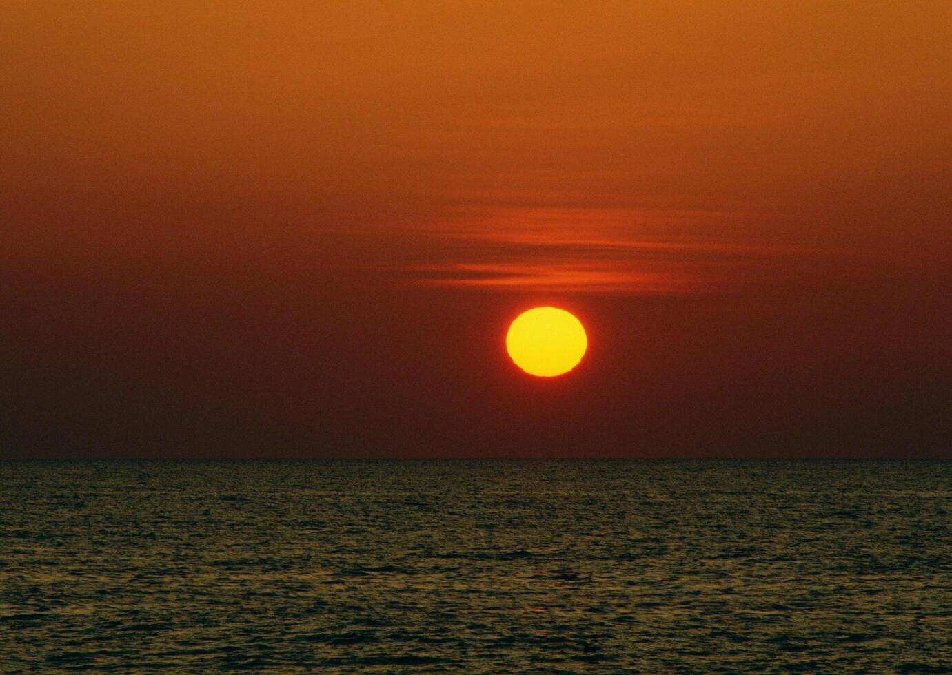 A large orange sun is seen in the sky photo