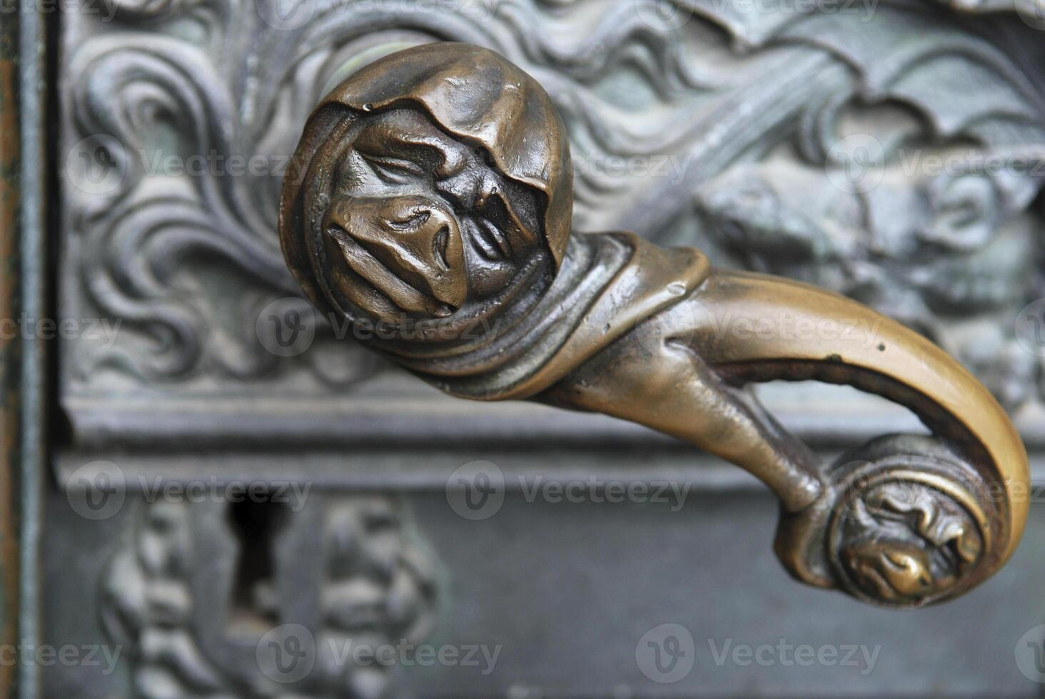 Doorhandle with grimace face and lock at a side portal of the cathedral of Cologne, NRW, Germany photo