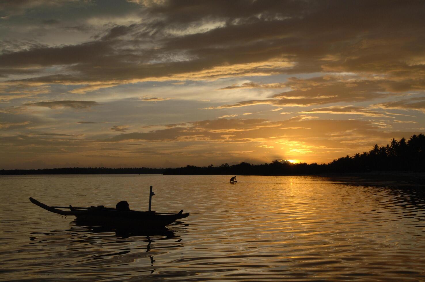 A boat is floating in the water at sunset photo