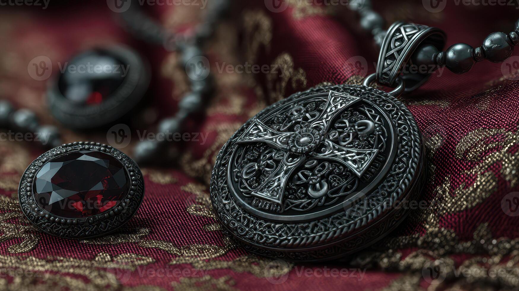 Intricate black cross pendant and matching gemstone on deep red fabric showcasing detailed craftsmanship photo