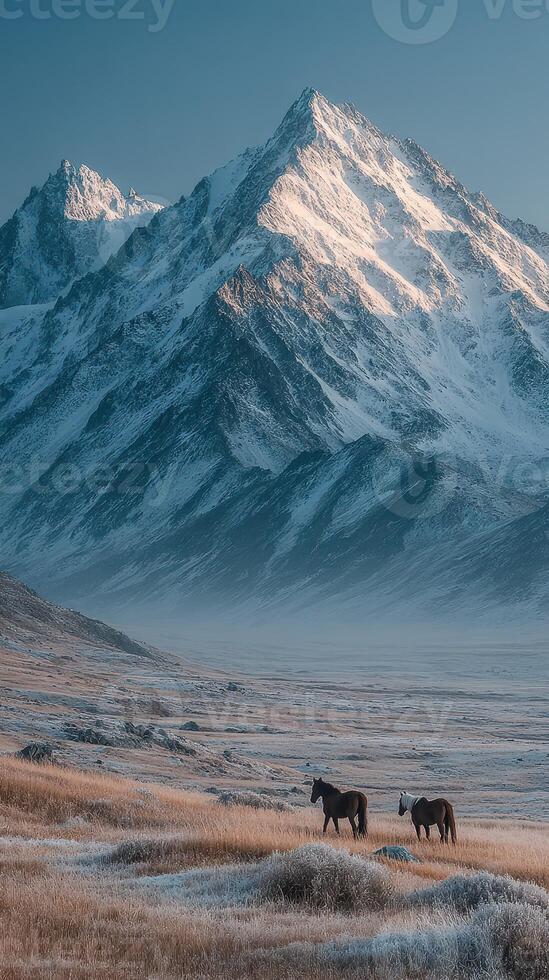 Horses grazing in a serene valley with majestic mountains during early morning light in a tranquil landscape photo