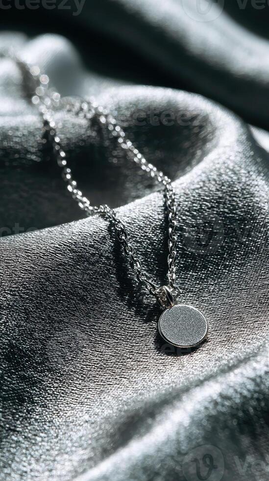 Silver necklace resting on satin fabric showcases elegance and simplicity with a circular pendant photo