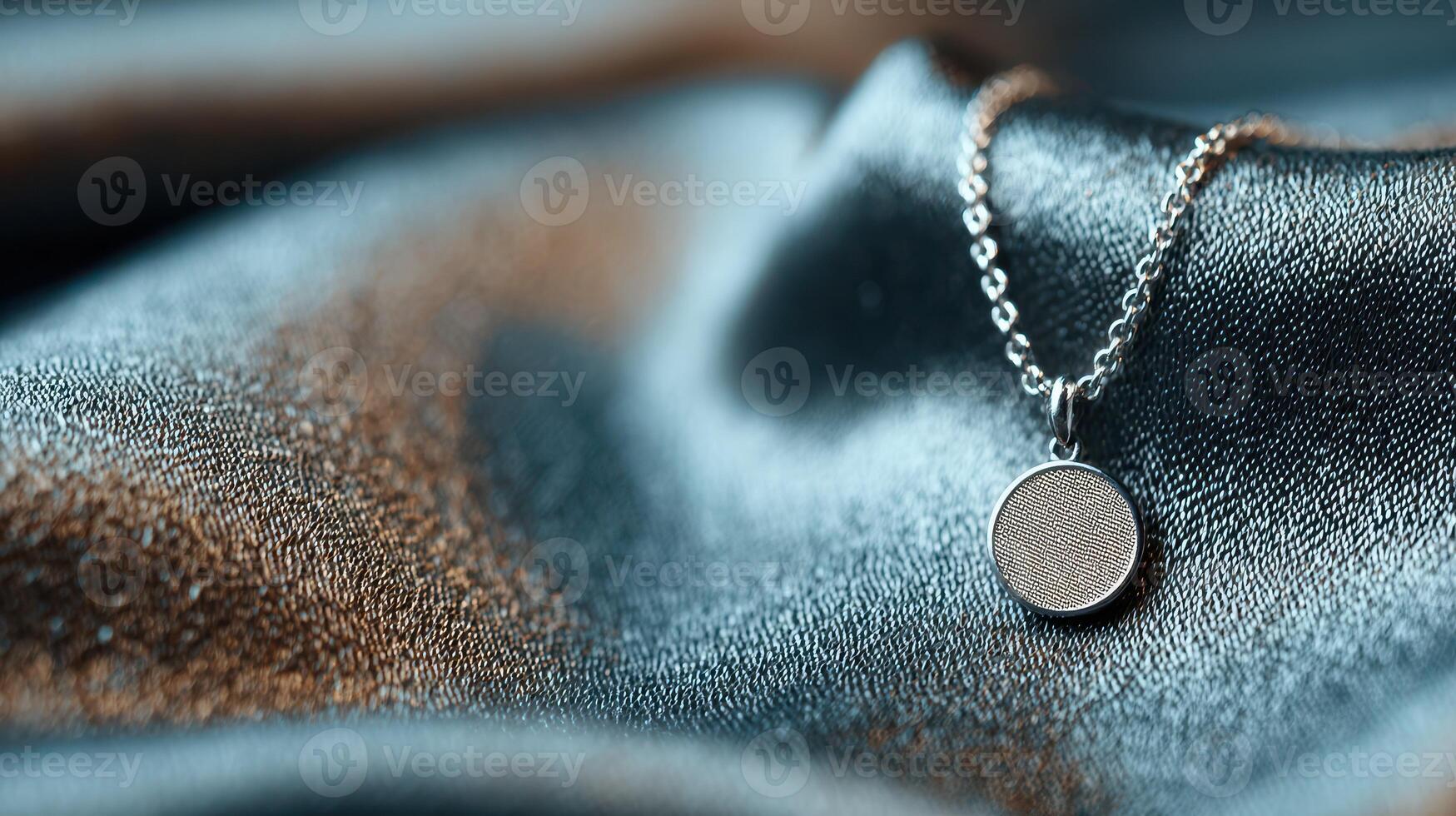 Silver pendant resting on a shimmering dark fabric background in a softly lit setting photo