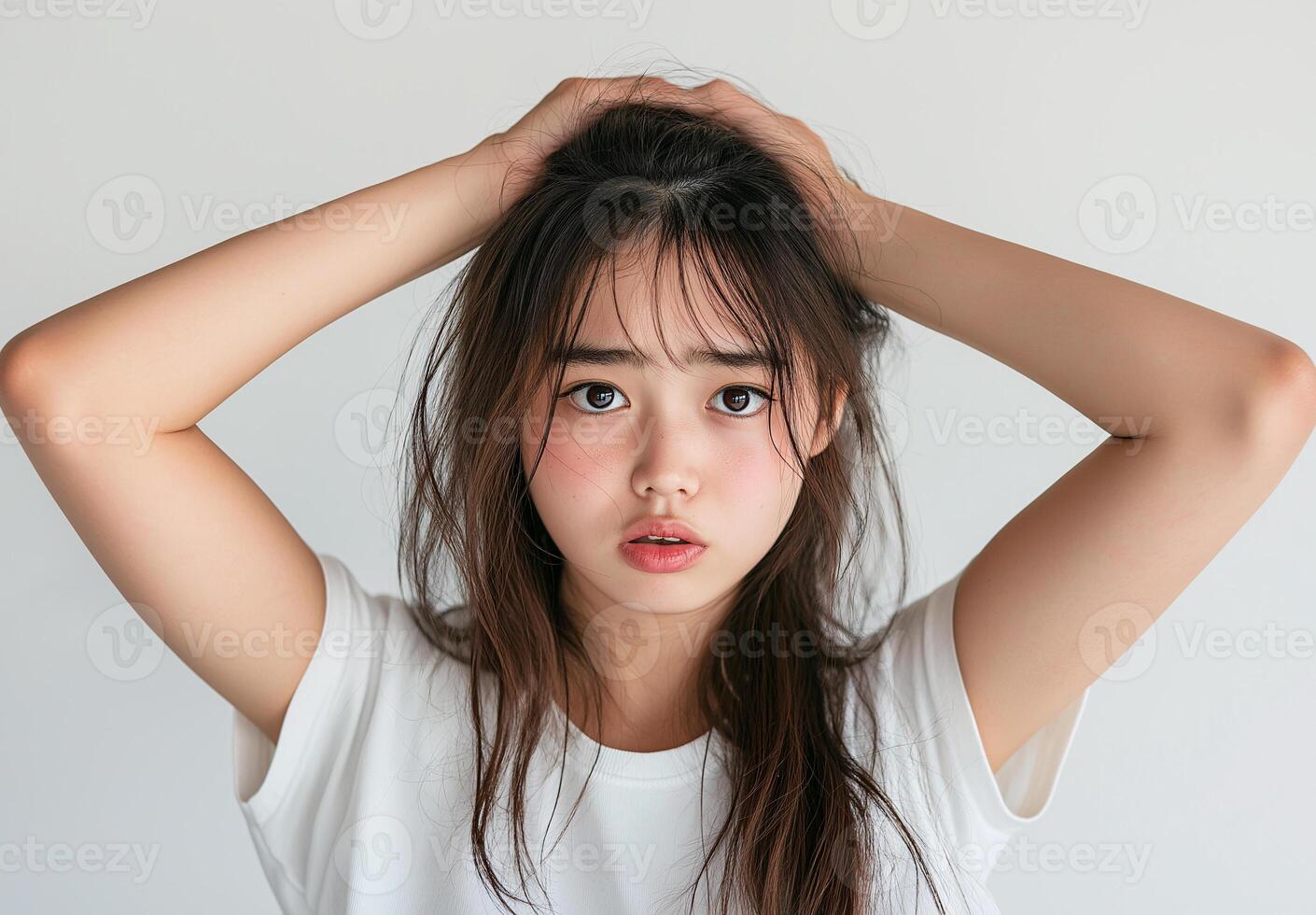 A woman with long hair is standing with her hands on her head photo