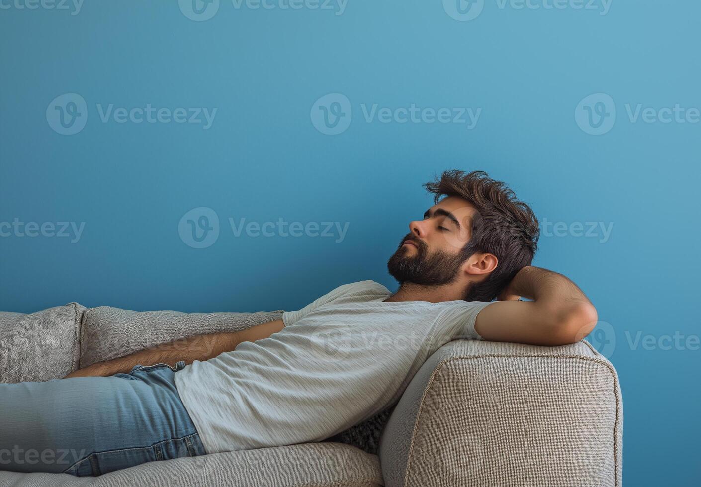 A man is laying on a couch with his head resting on his arm photo