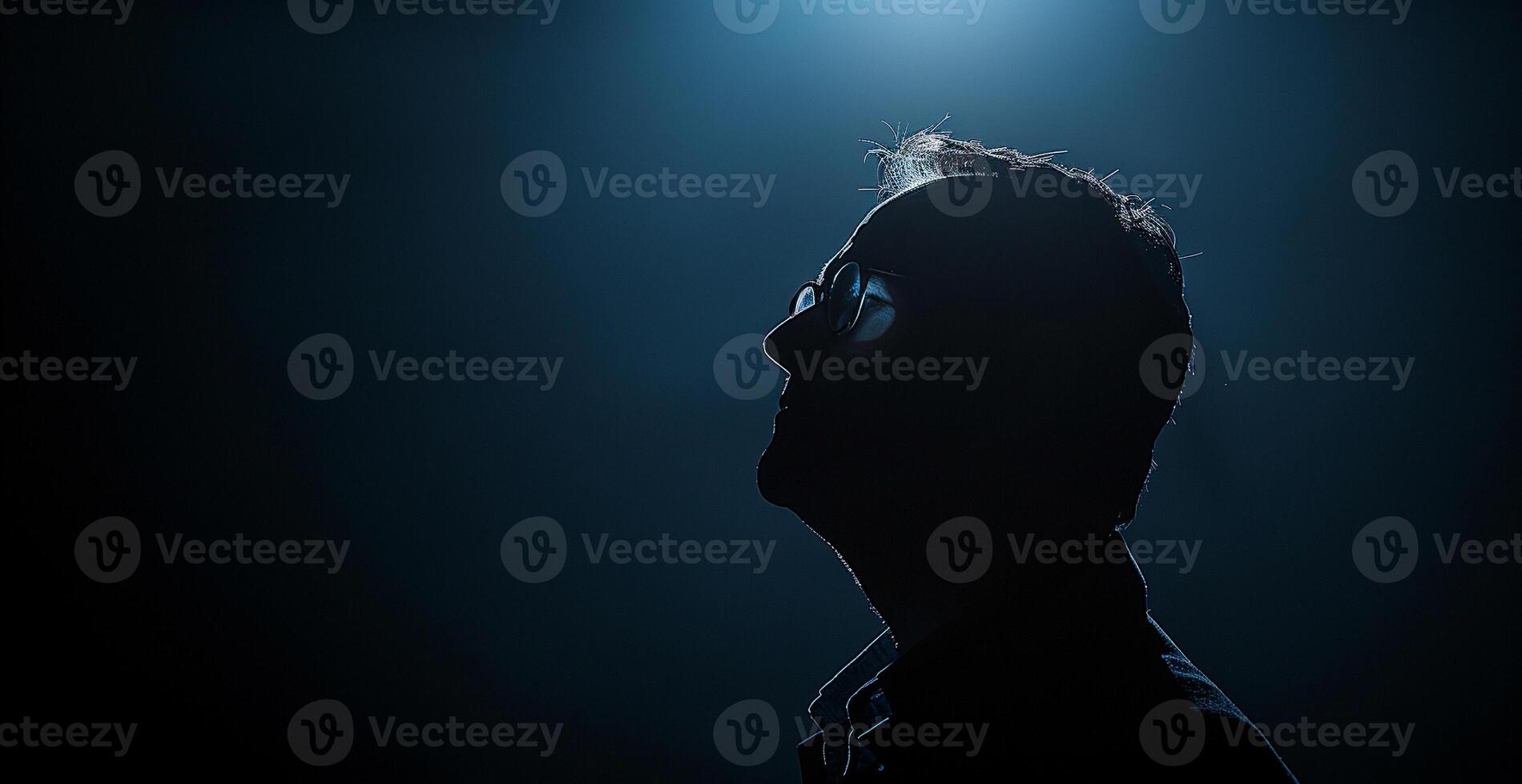 A man with glasses is standing in a dark room photo