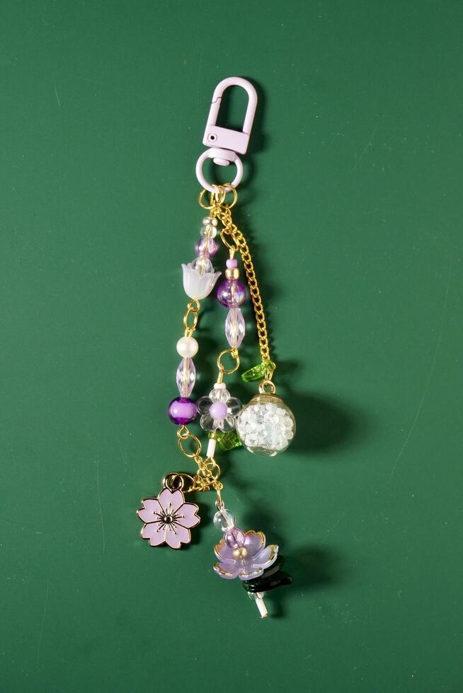 Beautiful flower beads and chain bag charm decorative keychain isolated on vertical ratio green background. photo