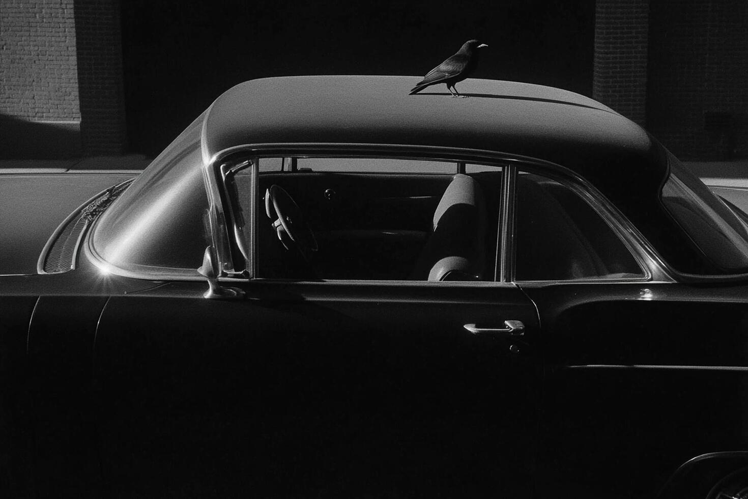 A black and white photo of a car with a bird perched on the roof