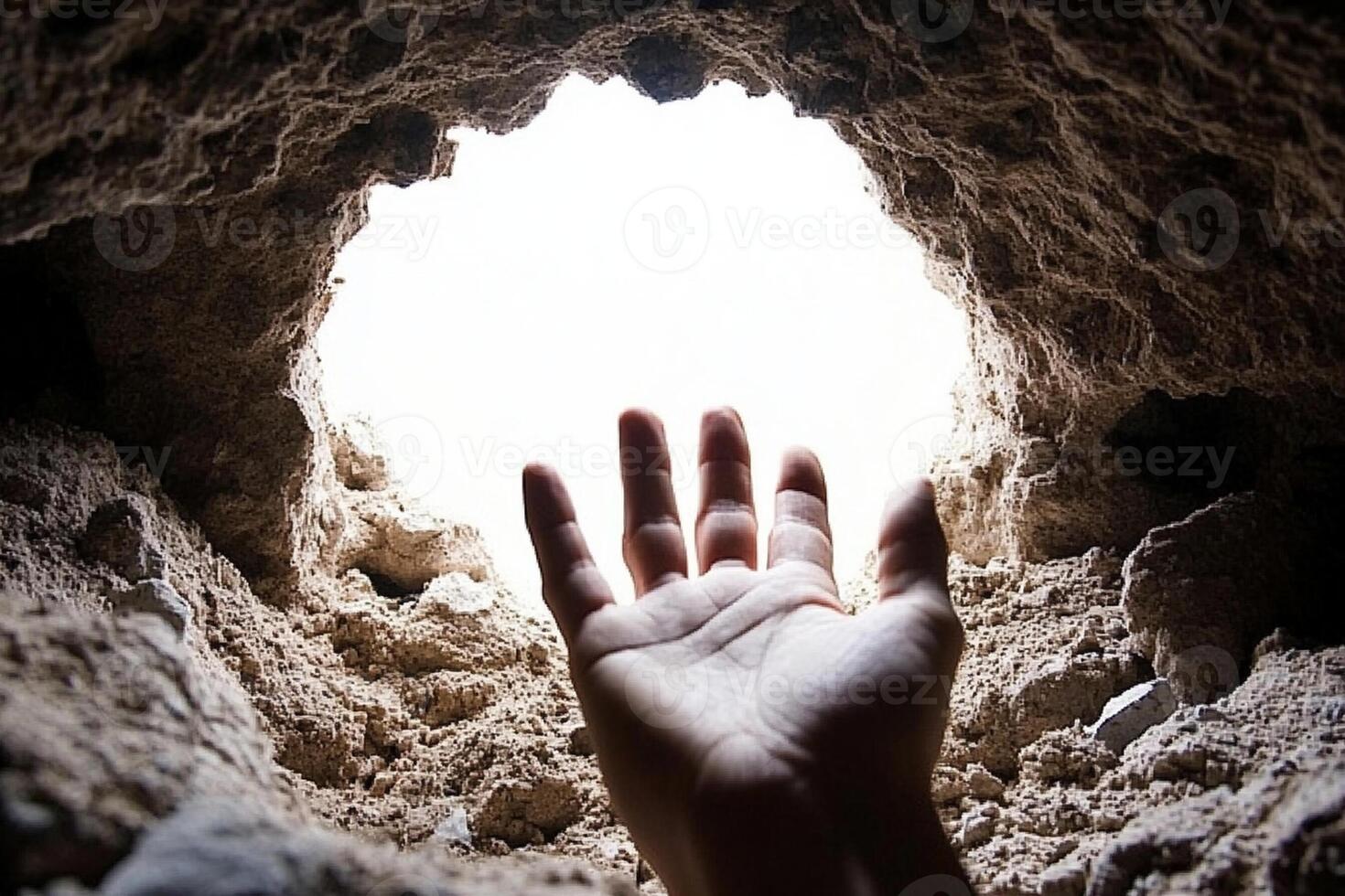 A person reaching out to the light from a cave photo