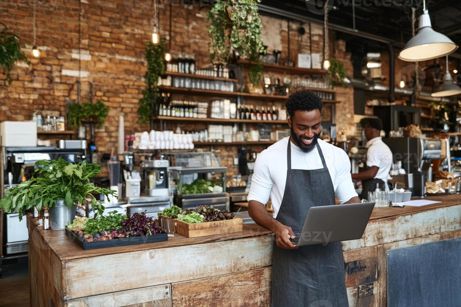 A man in an apron is standing in front of a laptop photo