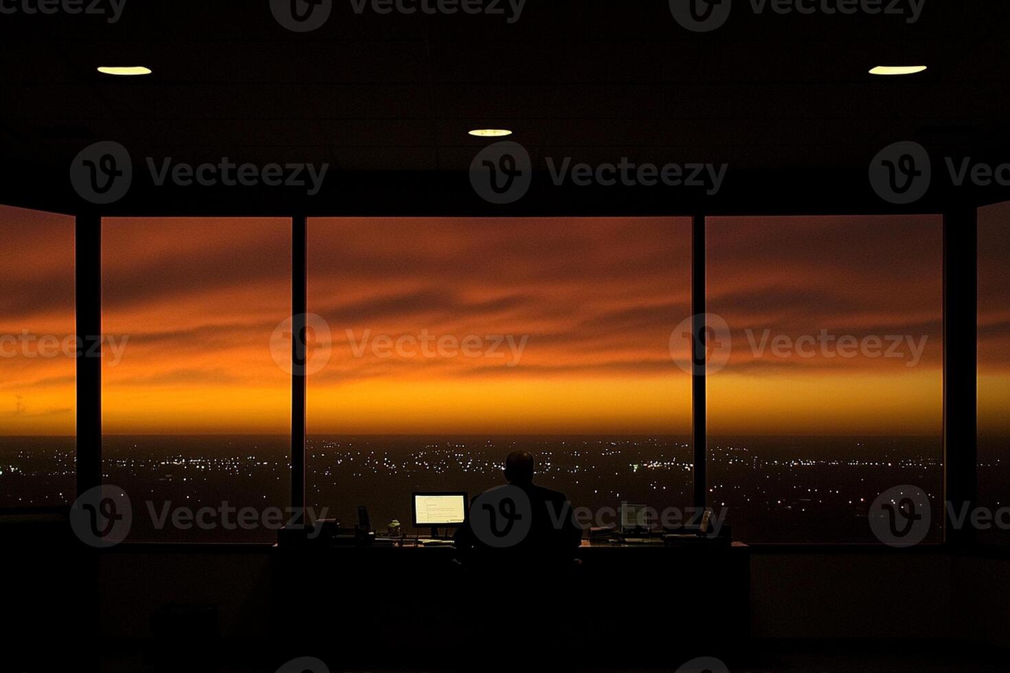 A person sitting at a desk in front of a window photo
