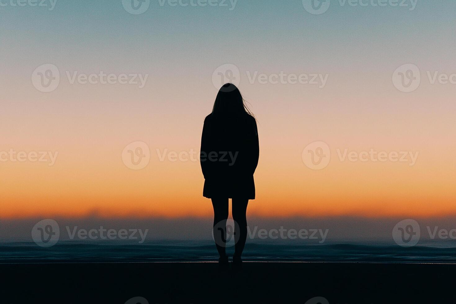 Silhouette of a woman standing on the beach at sunset photo
