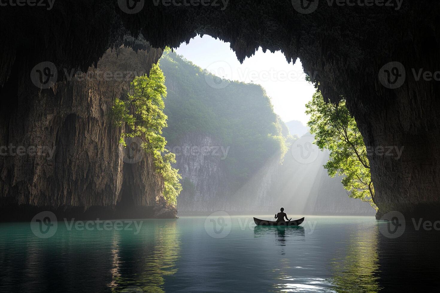 A man in a boat in a cave with sunlight coming through the water photo