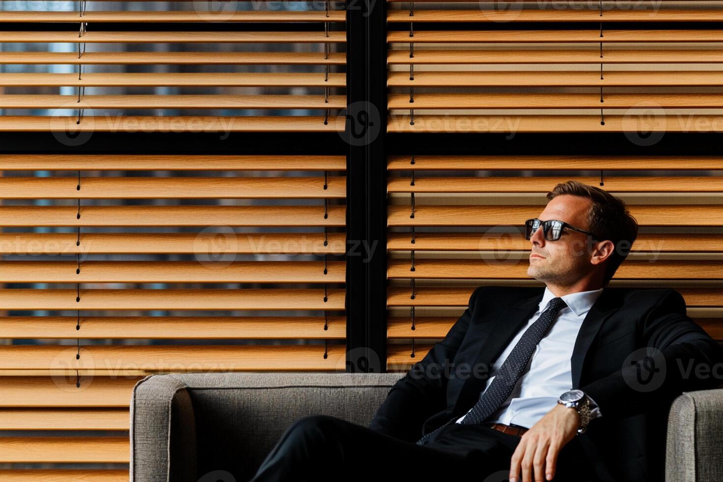 A man in a suit and sunglasses sitting on a couch photo