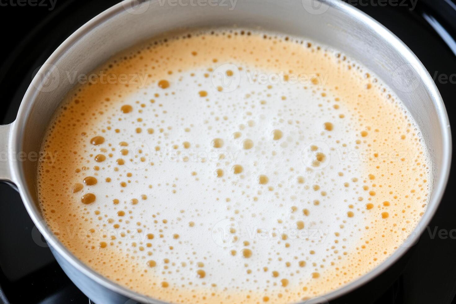 A pot of milk is being stirred in a pan photo