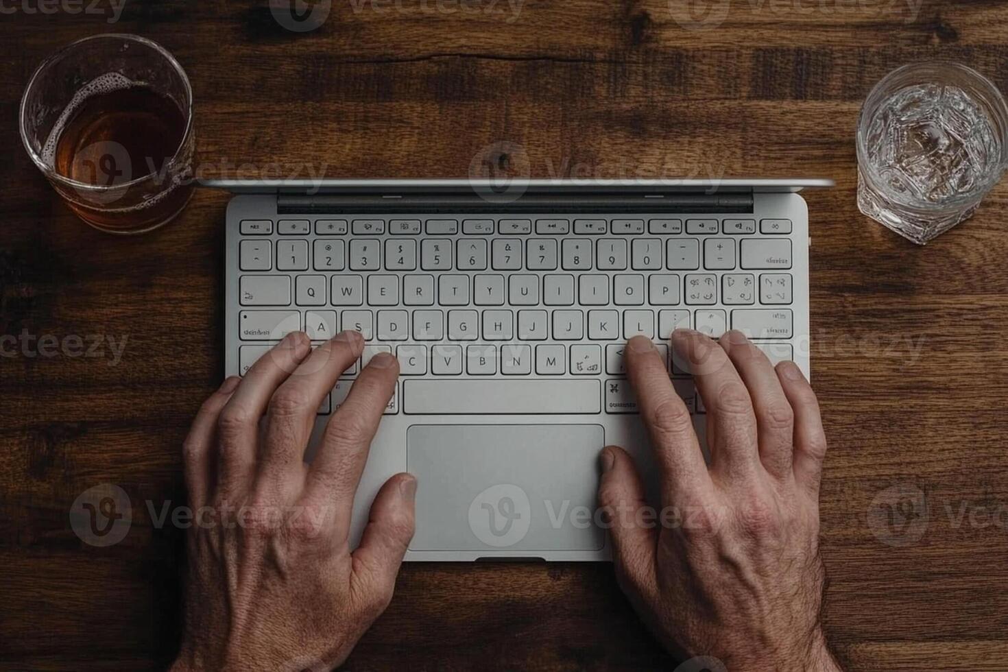 Hands typing on a laptop with a glass of beer photo