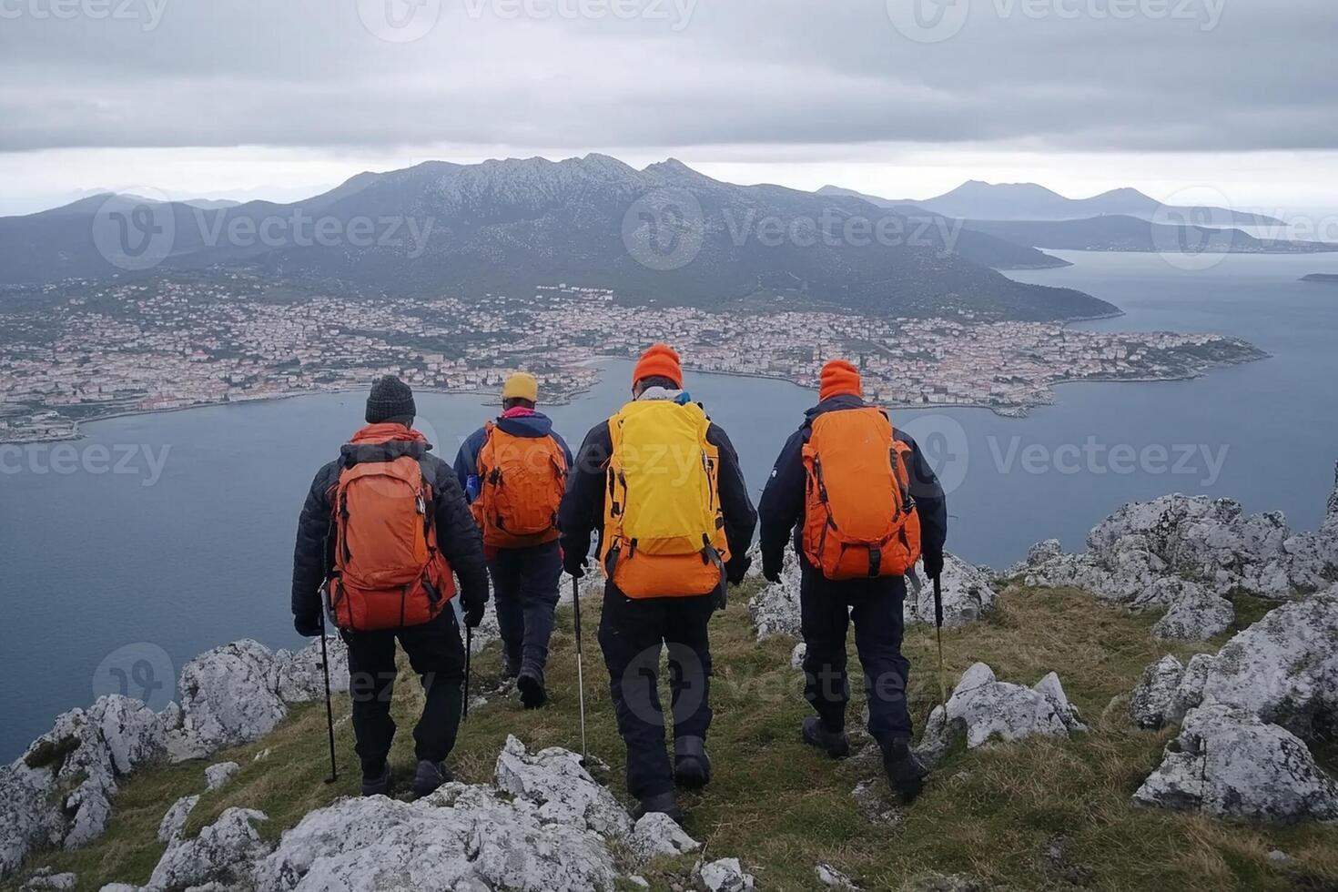 Four people with backpacks on a mountain overlooking a city photo