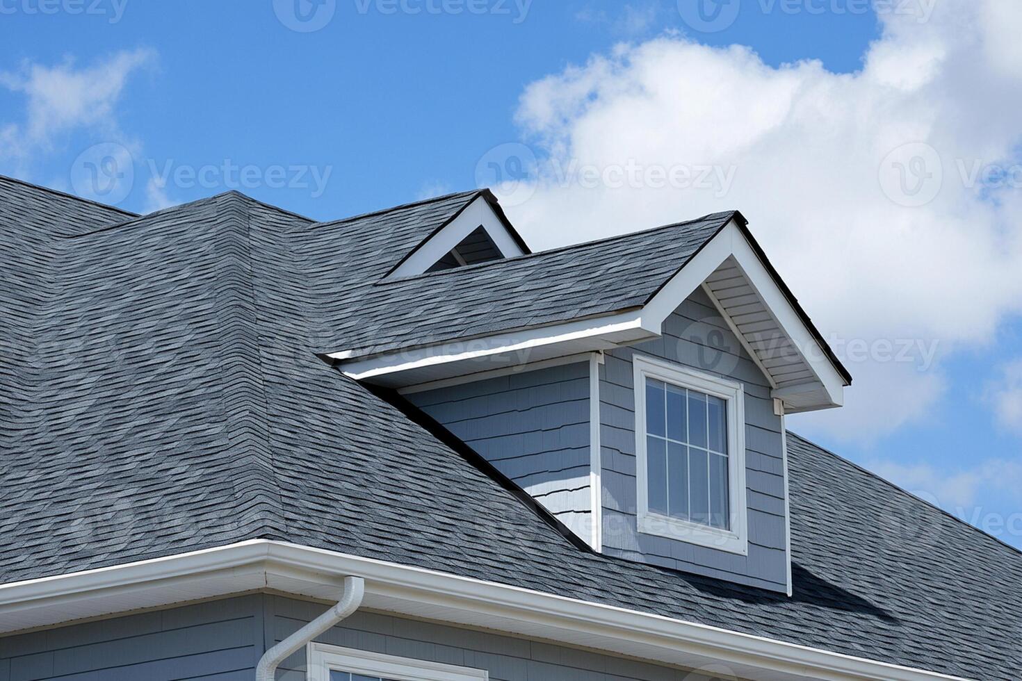 A roof with a gray shingled roof and a white window photo