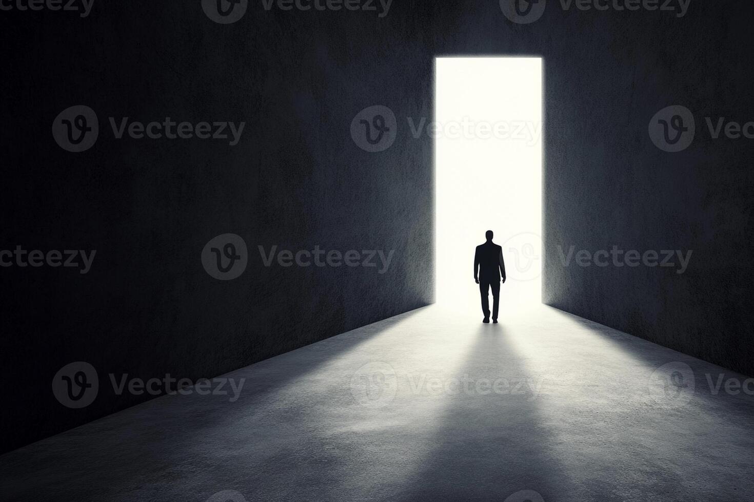 A man standing in an empty room with a light coming from the door photo