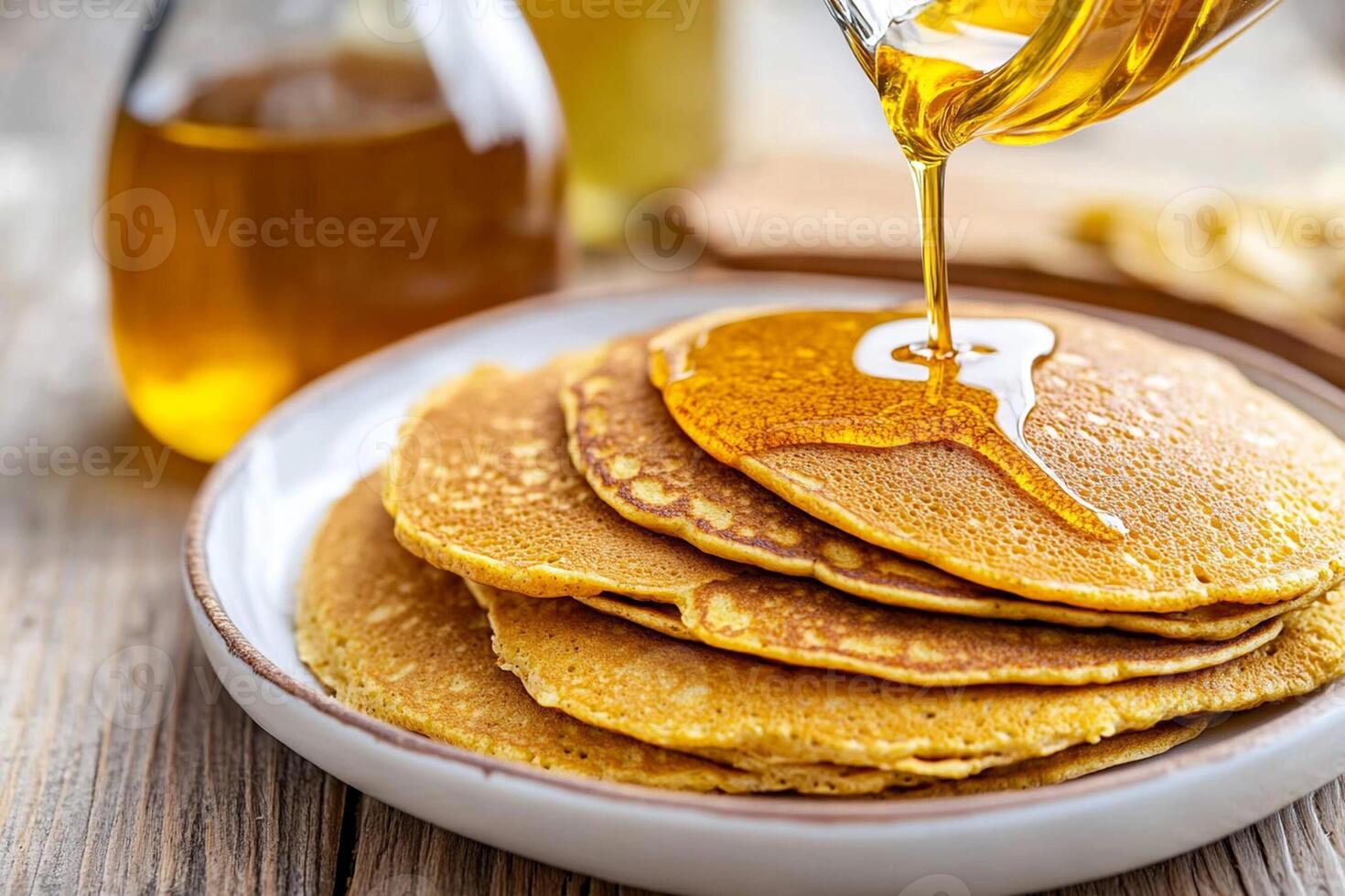 A stack of pancakes on a plate with syrup being poured on them photo