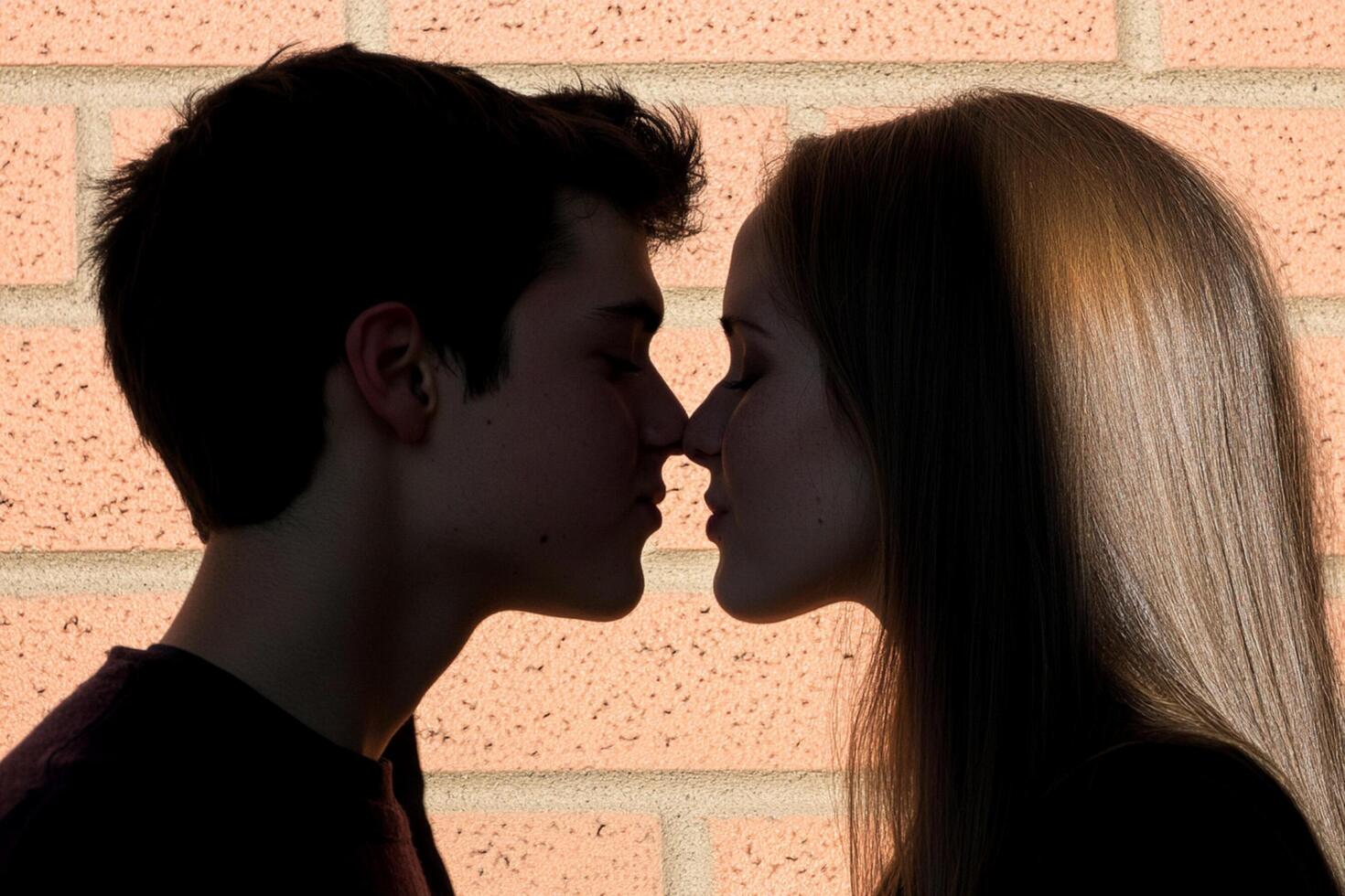 A young couple kissing in front of a brick wall photo