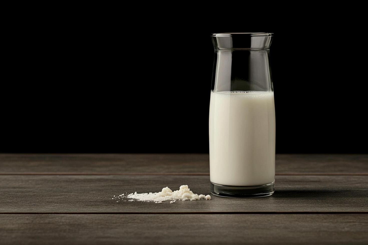 A glass bottle of milk sits on a table photo