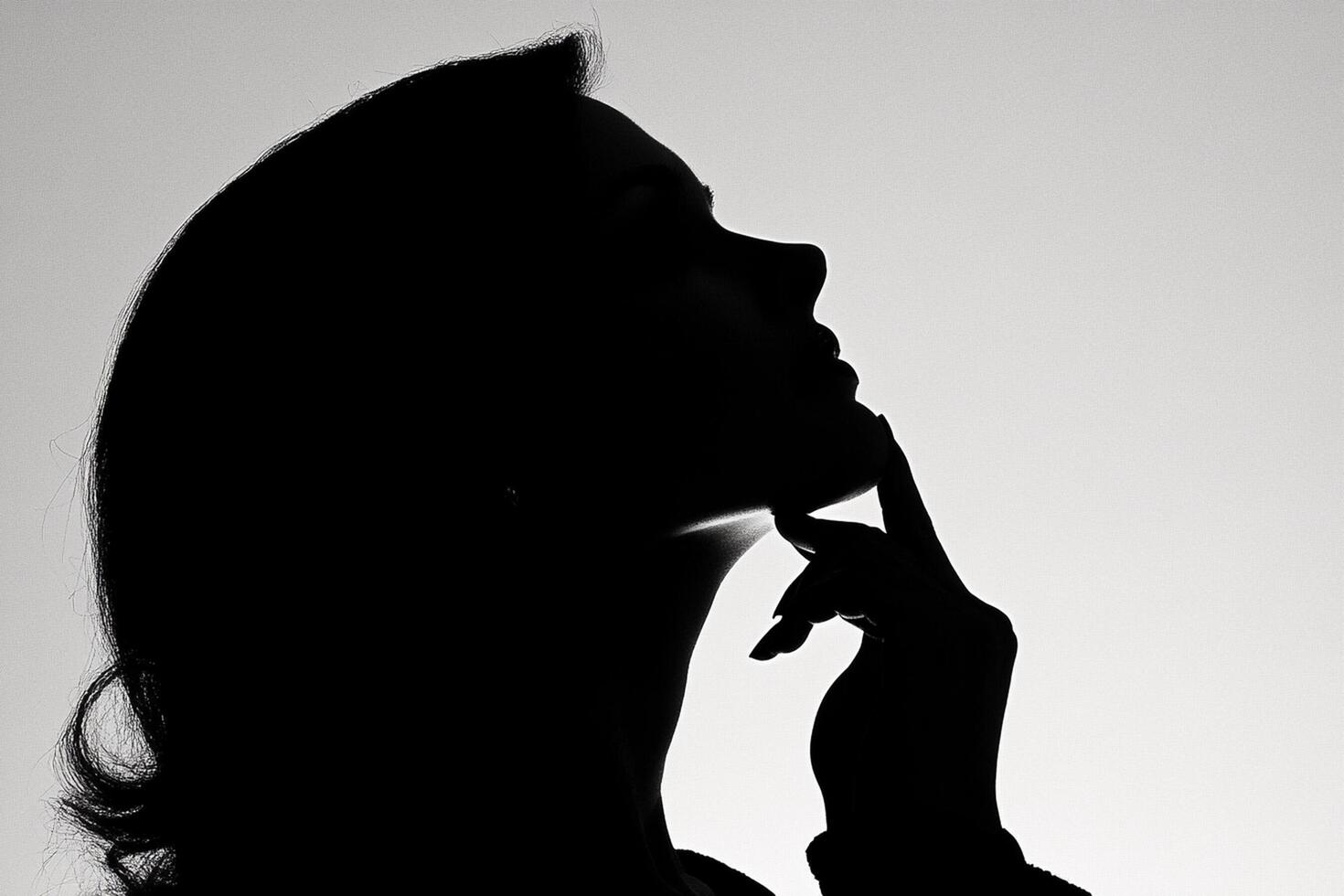 A woman in silhouette with her hand on her chin photo