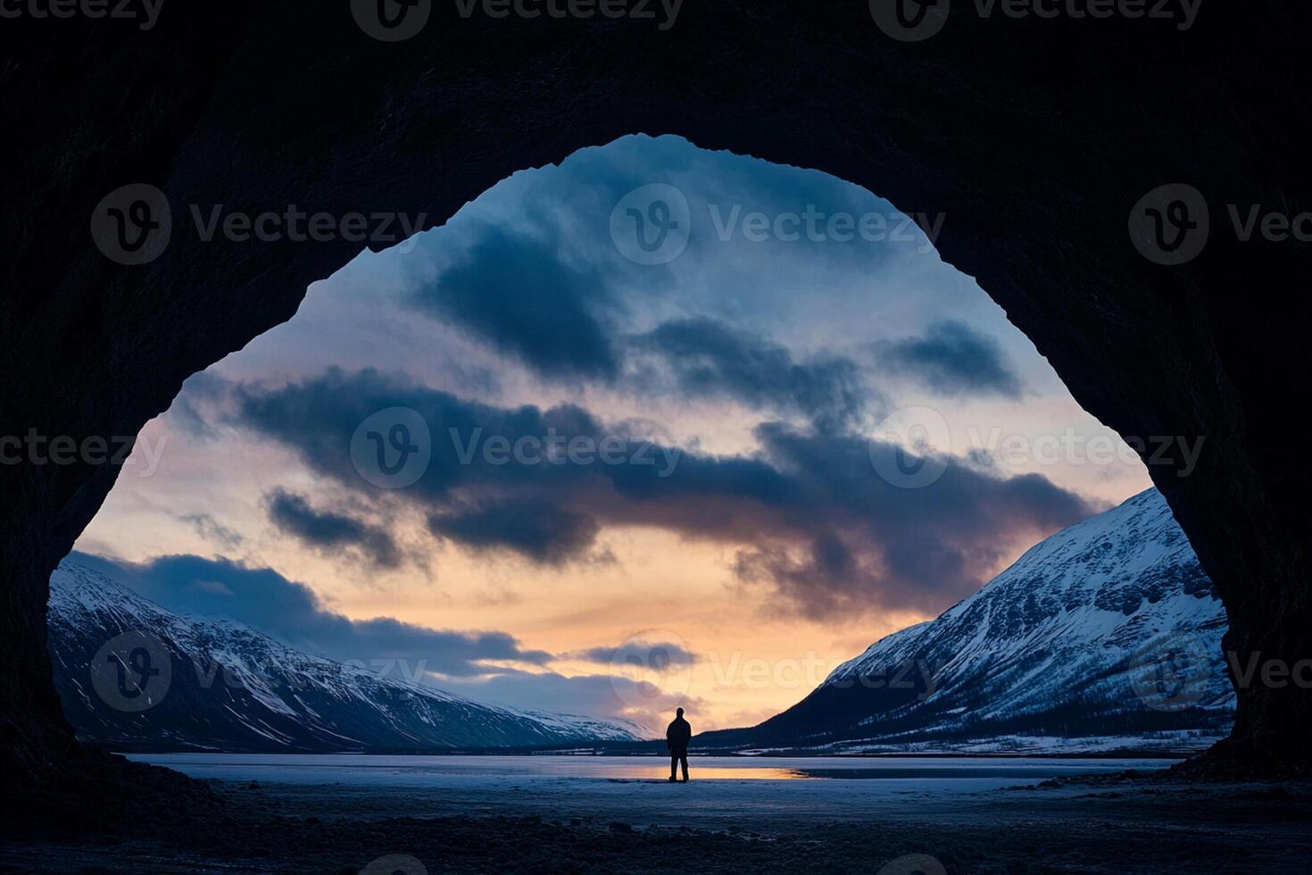 A person standing in front of a cave at sunset photo