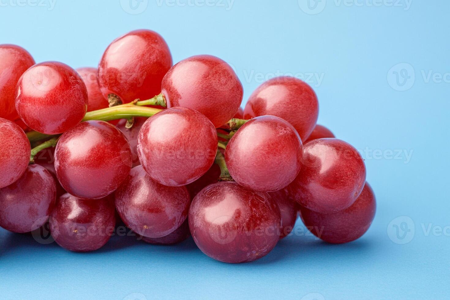 A bunch of red grapes on a blue background photo