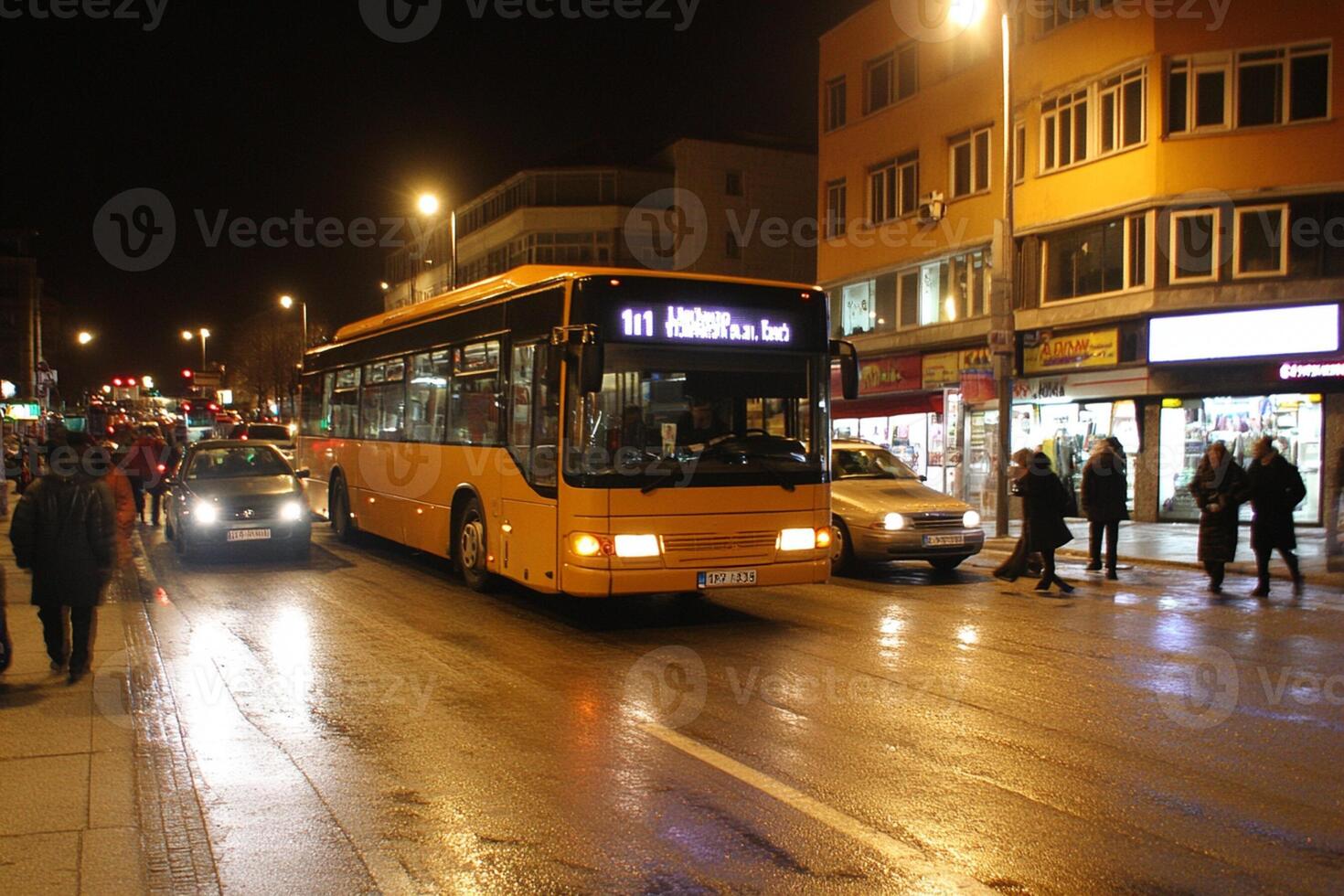 A yellow bus driving down a street at night photo