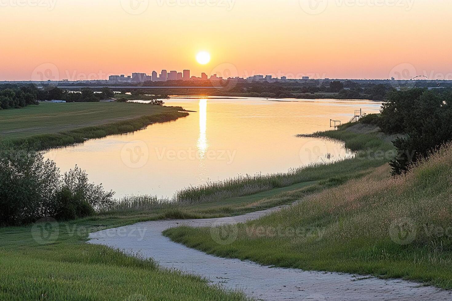 A river runs through a grassy field with a city in the background photo