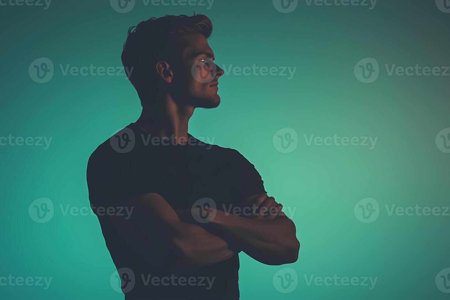 Confident male model posing with crossed arms on teal background photo